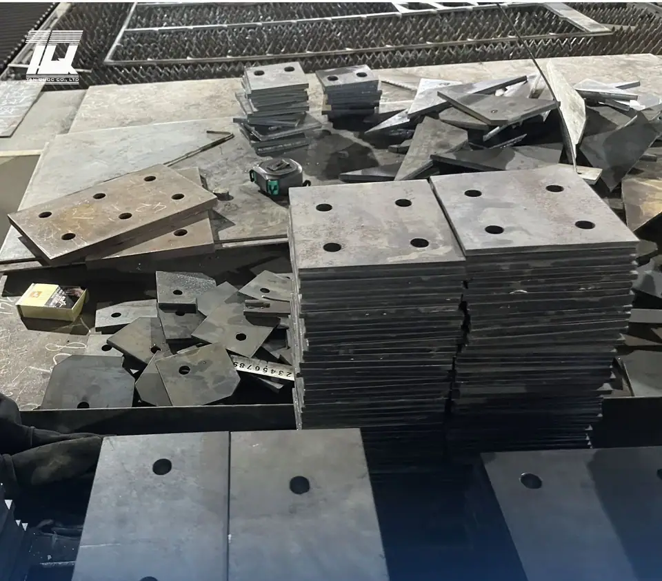 Các chồng bản mã thép đã cắt CNC và khoan lỗ sẵn tại xưởng Tấn Quốc
